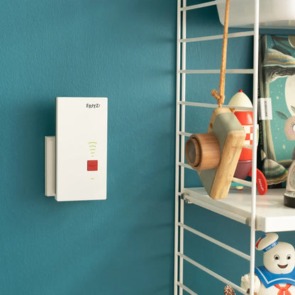 FRITZ!Repeater 2700 an der Wand in modernem Raum, umgeben von dekorativen Gegenständen.